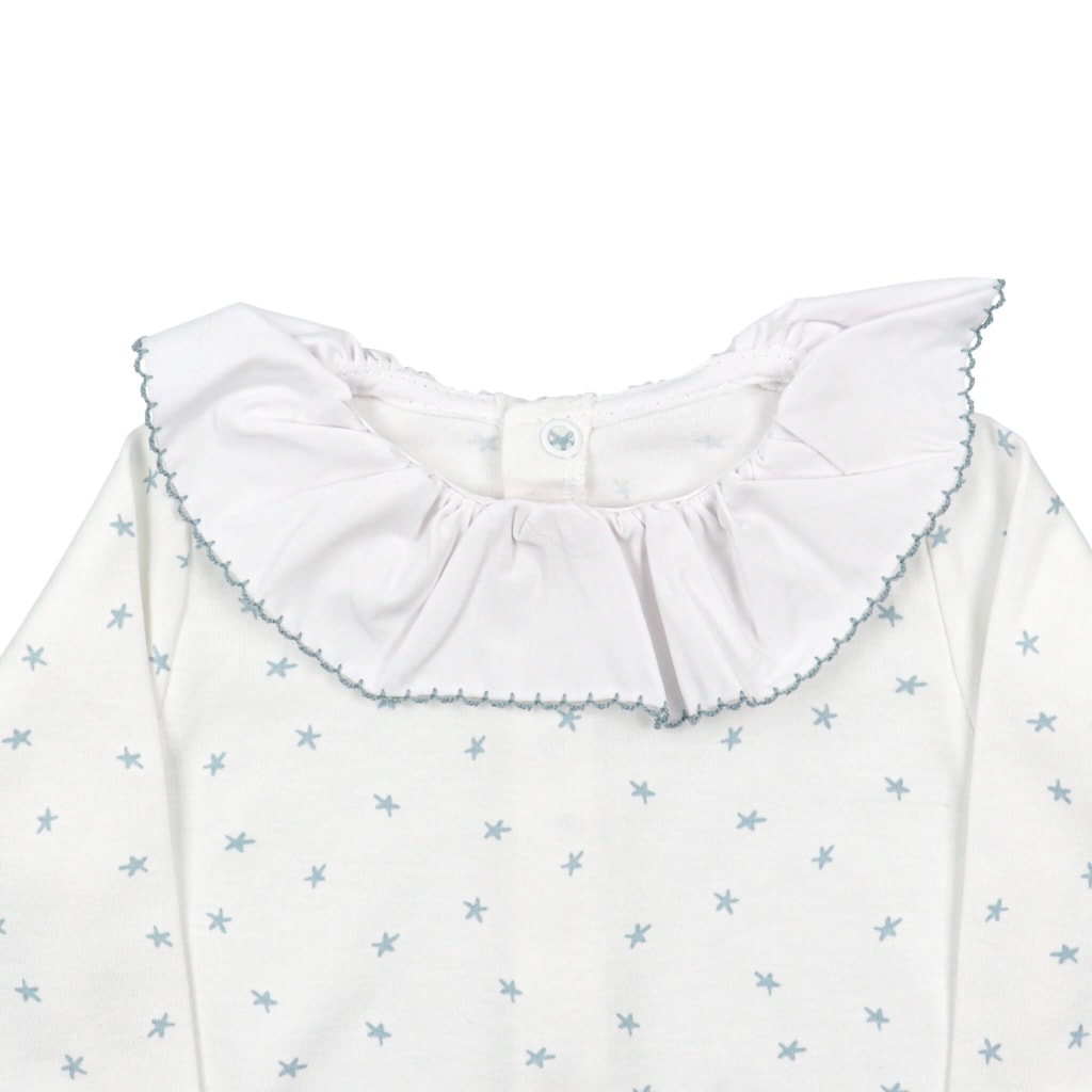 Pormenor da gola em tecido de babygrow de bebé branco cru com estrelas azuis.