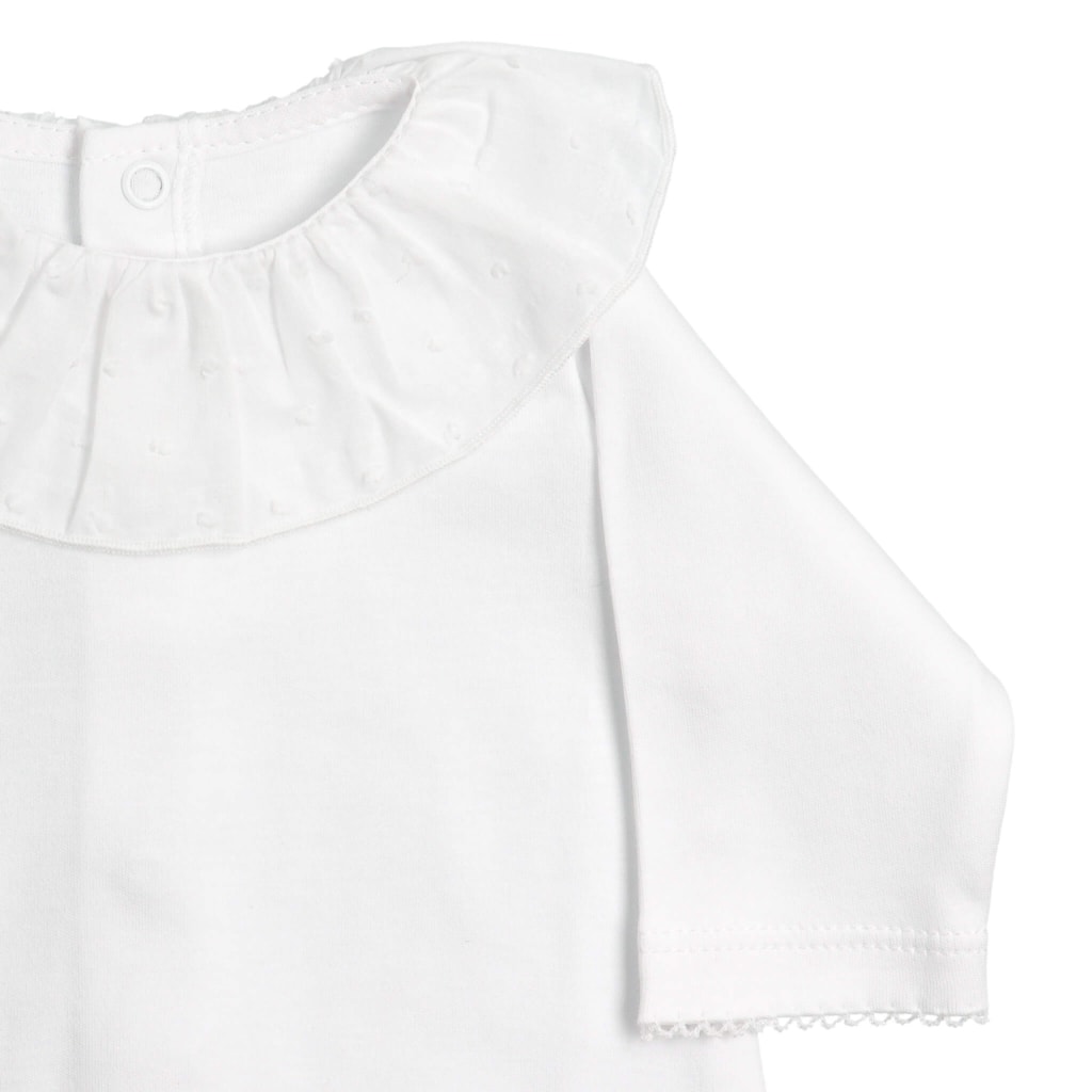 Pormenor da gola e da manga de um babygrow para bebé feito em tecido de algodão branco com a gola em tecido plumeti branco.