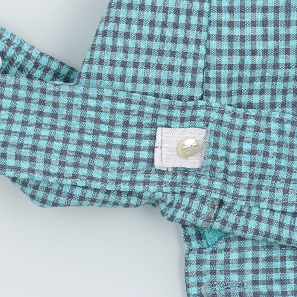 Elástico ajustável com botão no interior da cintura de uns calções de bebé aos quadrados azul turquesa.