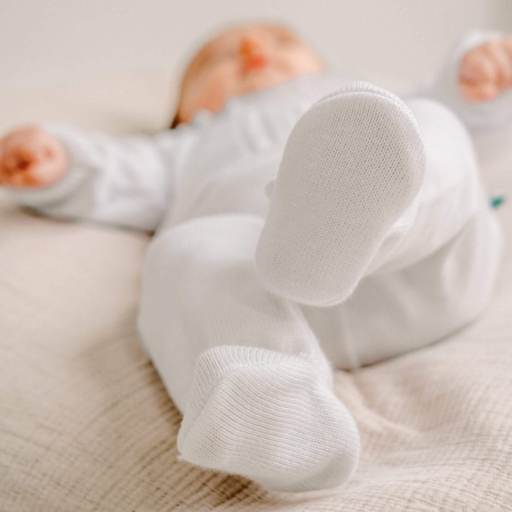 Bebé deitado vestido com um conjunto de malha feito de camisola e calças de algodão.