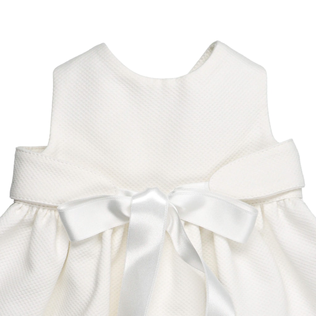 Cueiro para bebé em tecido de piquet pérola com uma fita de cetim branca à frente que fecha em laço.