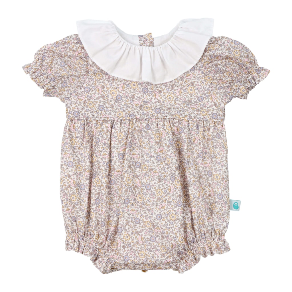 Fofo para bebé com manga curta feito em tecido de padrão de flores. Tem as mangas com franzido e uma gola de tecido branca.