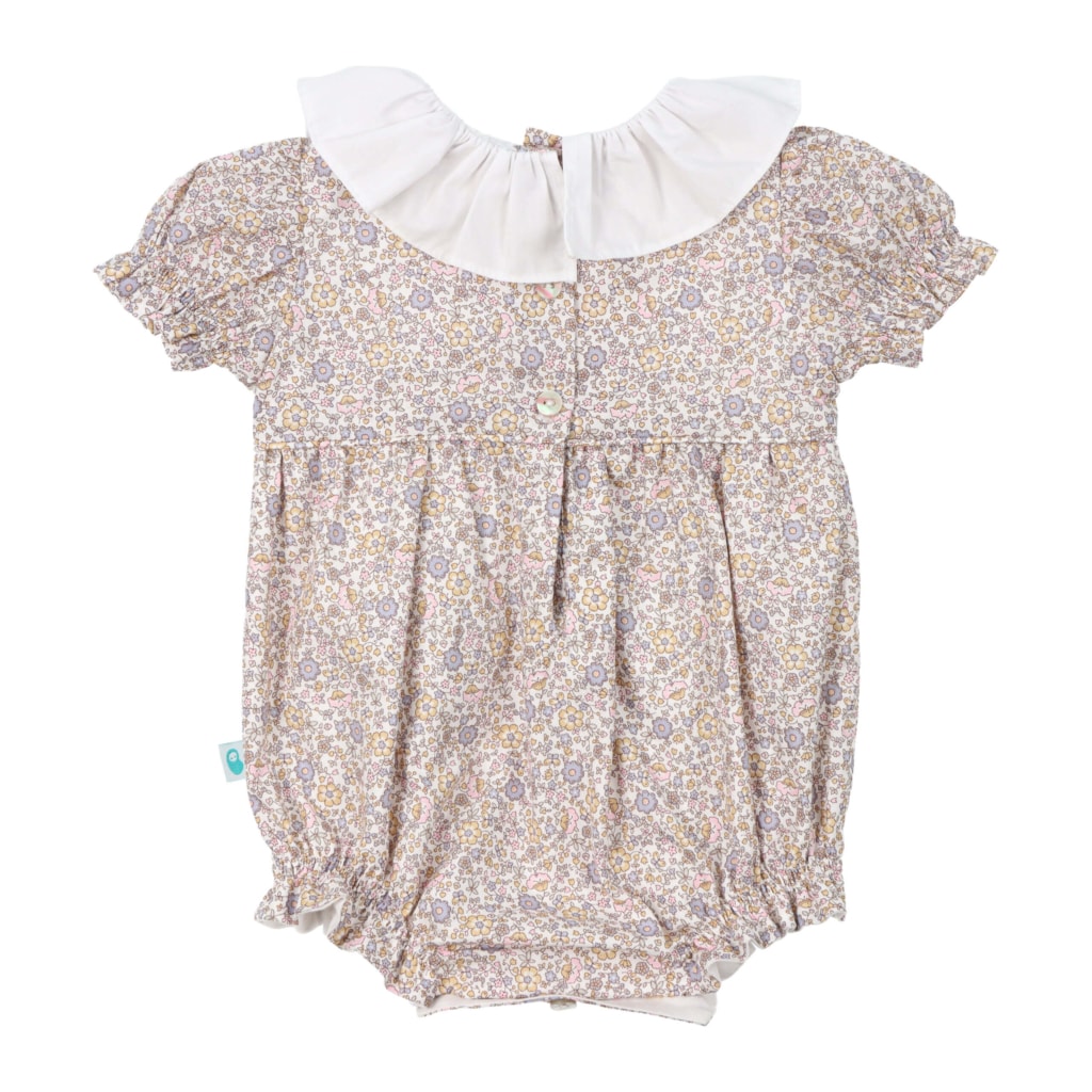 Vista de costas de um fofo de bebé em tecido de padrão com flores e uma gola branca em tecido.