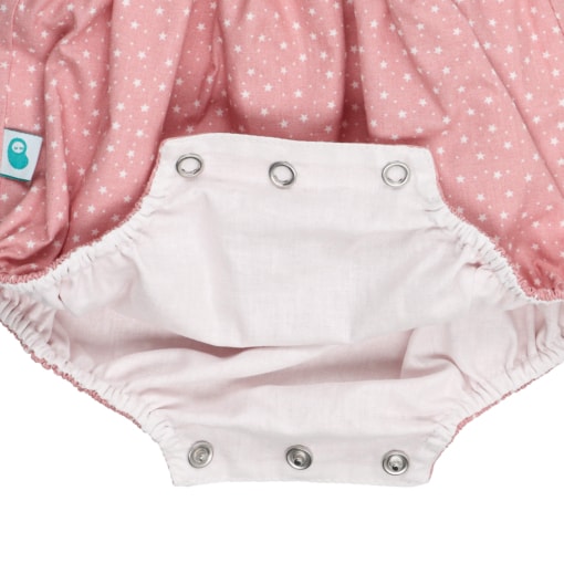 Forro branco e molas de pressão do entre-pernas de um fofo de bebé em tecido de algodão rosa com estrelas brancas estampadas.