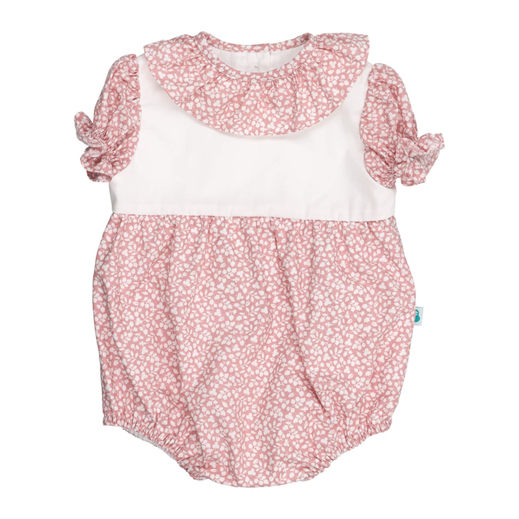 Fofo de bebé com manga curta com folhos. É feito em tecido rosa claro com padrão de flores brancas estampado e tem a gola em tecido a condizer.