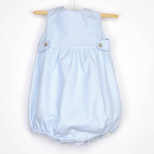 Fofo para bebé feito em tecido de algodão com padrão aos quadrados azul. Aperta no peito com botões em madrepérola e trespasse nas costas. Tem elástico nas pernas e aperta com molas de pressão no entrepernas.