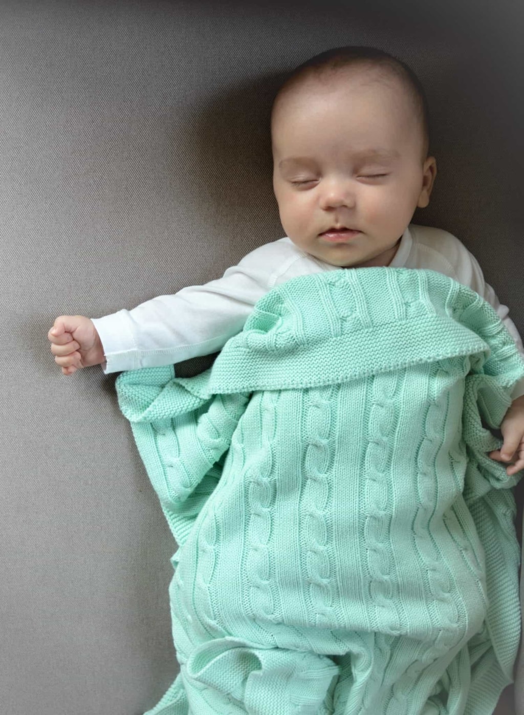 Bebé coberto com manta de algodão e cor verde.