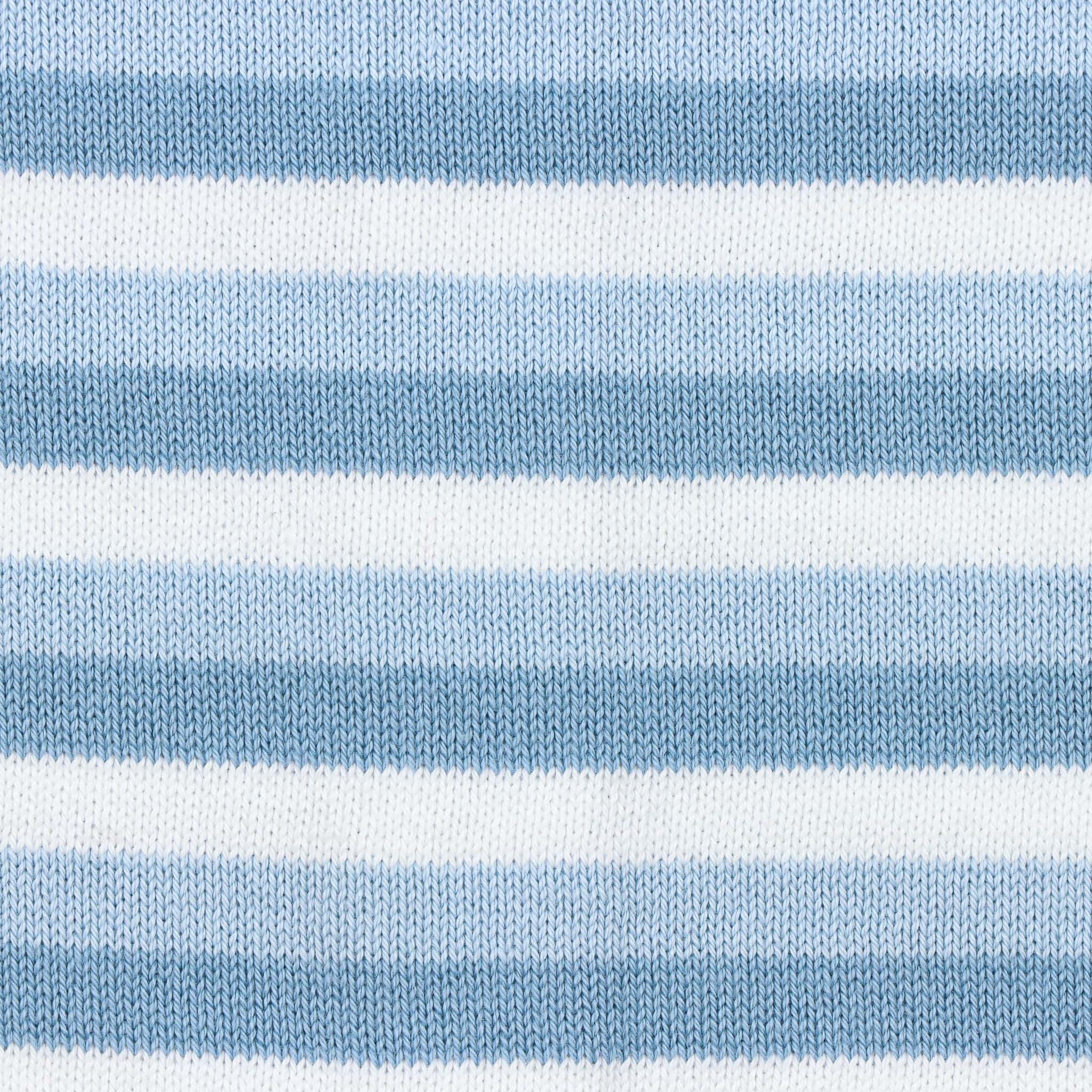 Detalhe de tecido em malha tricotada e padrão de riscas brancas, azul bebé e azul acinzentado, do macacão para bebé em algodão.