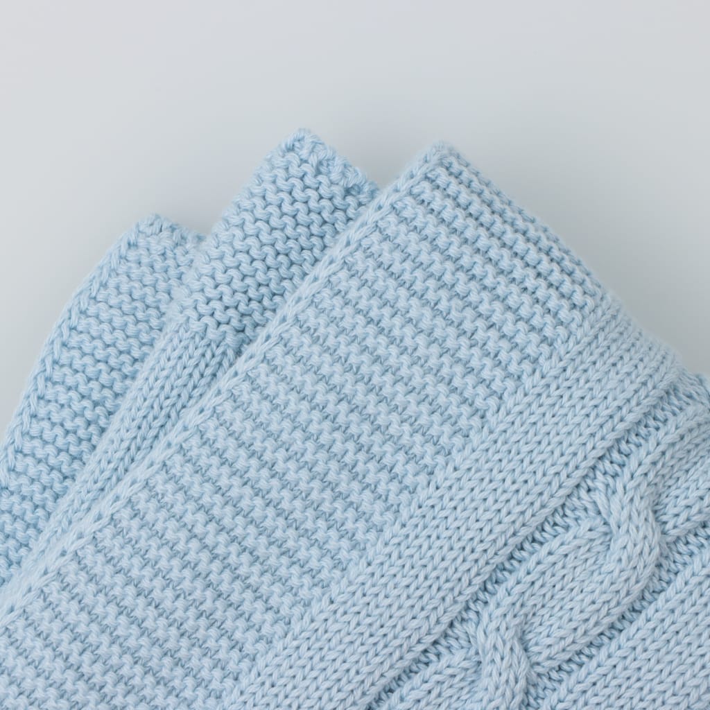 Pormenor do tecido em mala de algodão de uma manta para bebé azul com padrão de tranças.