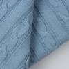 Pormenor do tecido em mala de algodão de uma manta para bebé azul inglês com padrão de tranças.