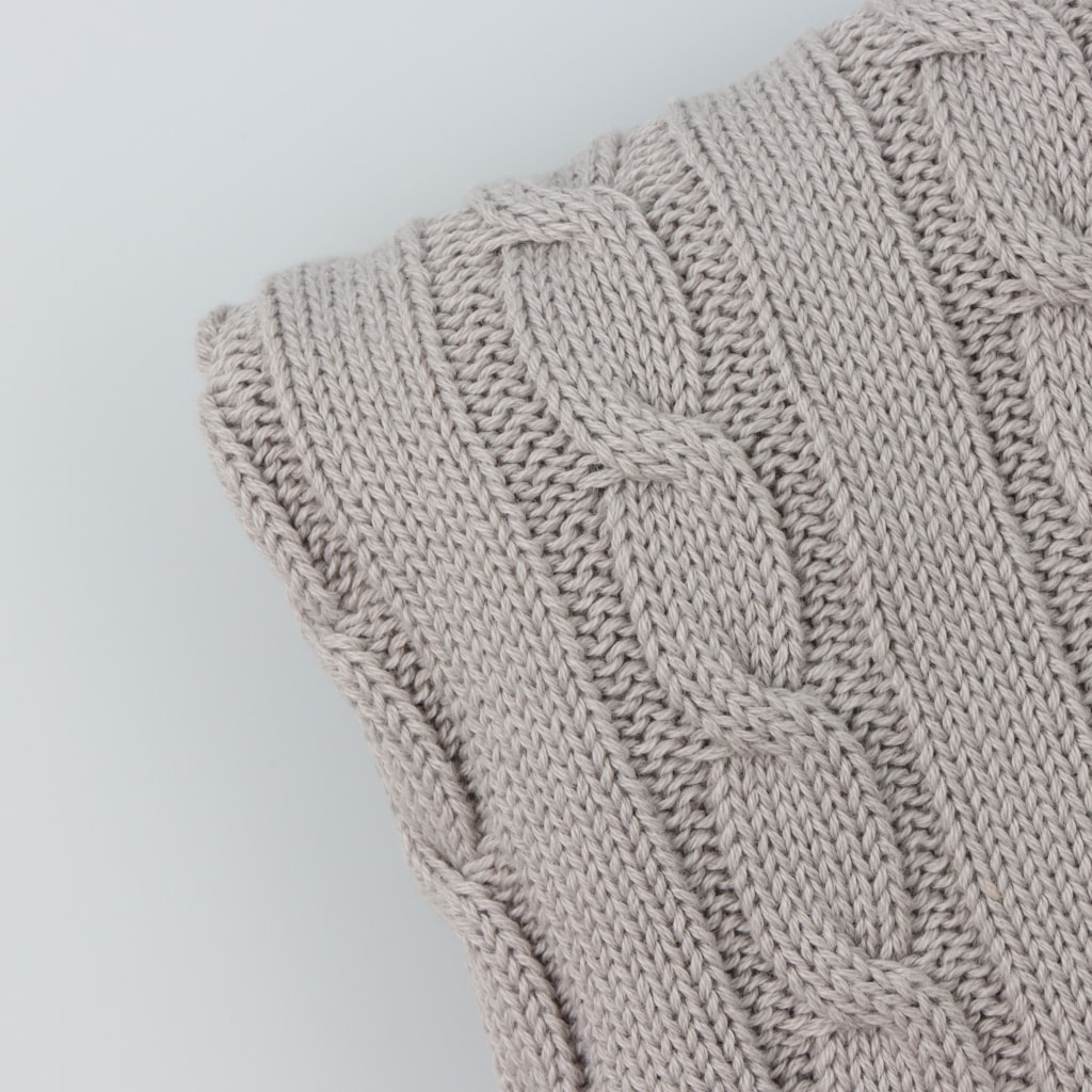 Pormenor do tecido em mala de algodão de uma manta para bebé cinzenta com padrão de tranças.