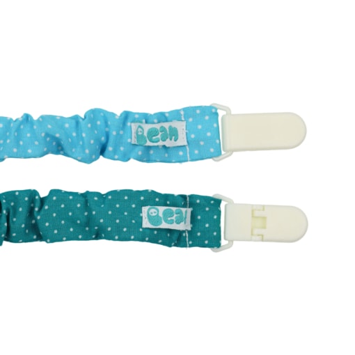 Dois prende chupetas feitos em tecido de muselina, um deles azul com pintas brancas e o outro verde com pintas brancas. Têm o fecho em plástico branco.