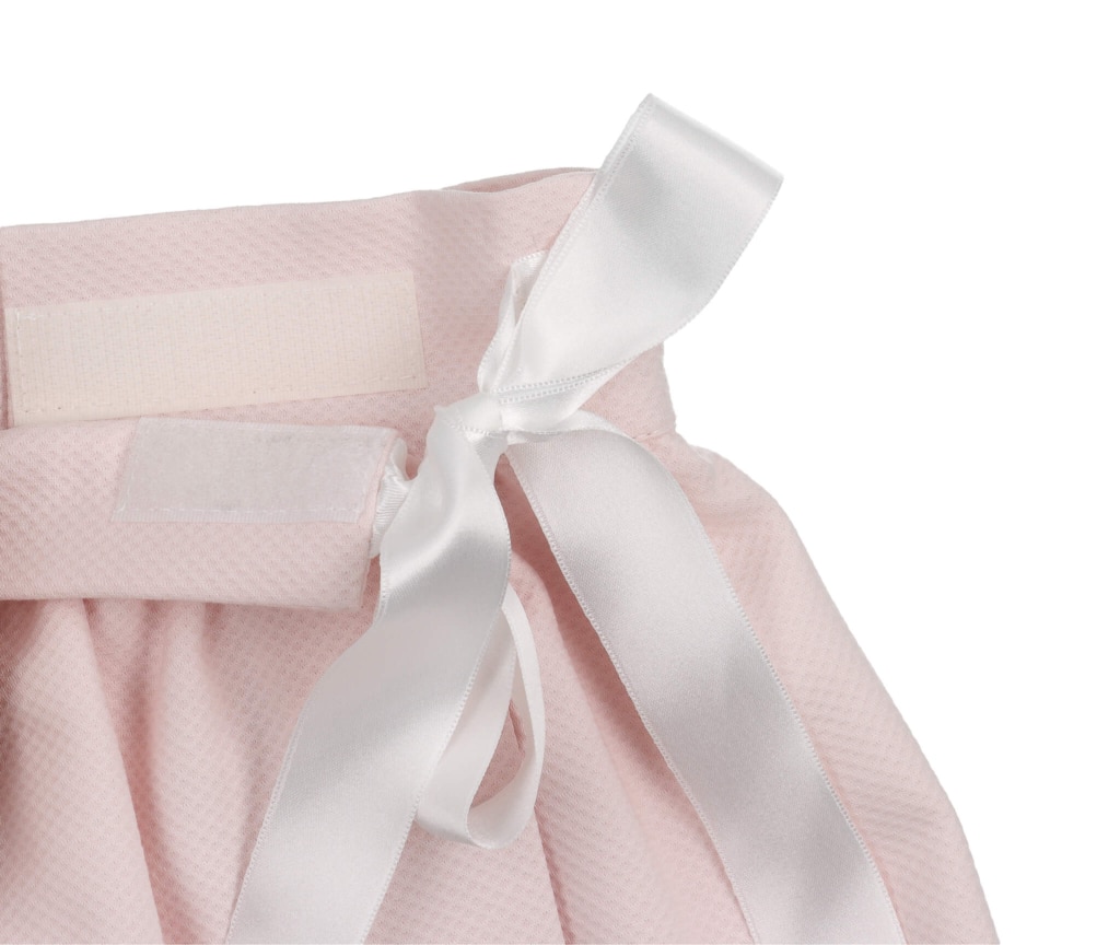 Saial de bebé em tecido piquet rosa com uma fita de cetim branca.