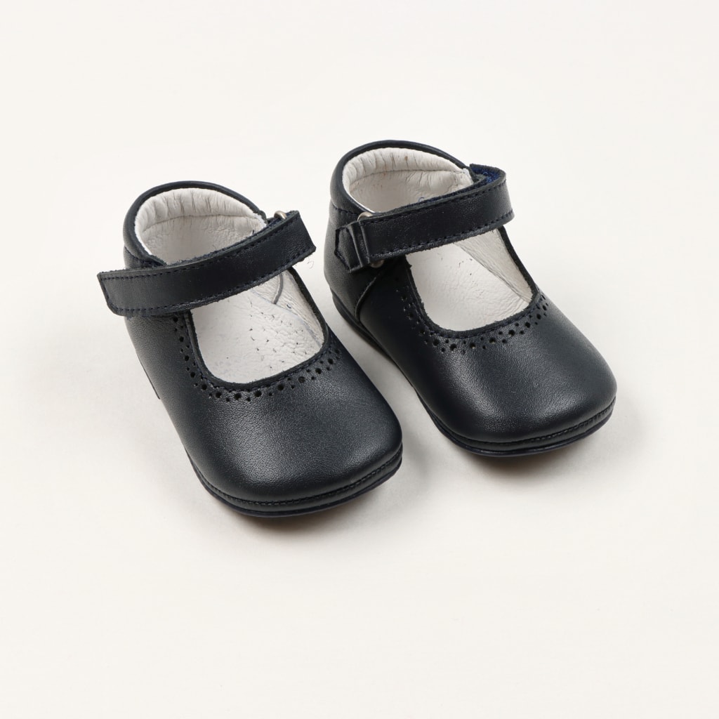 Sapatos de bebé feitos em pele de cor azul marinho. Apertam com uma fivela e têm o interior branco.