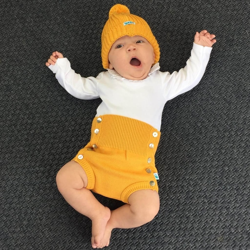 Bebé vestido com um gorro de malha e um tapa fraldas da mesma cor.