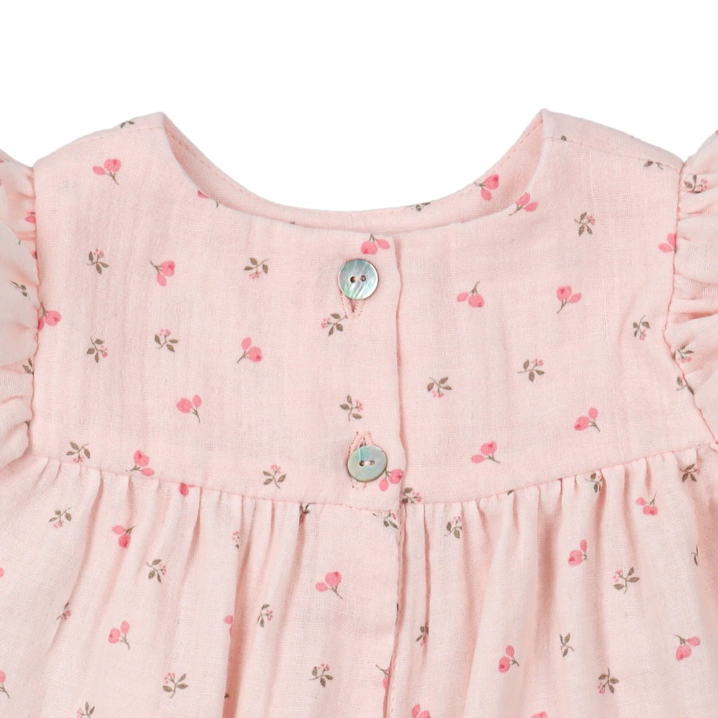 Botões de madrepérola de Vestido de bebé rosa com estampado em flores. Tem manga curta com folhos e é feito em tecido100% algodão orgânico.