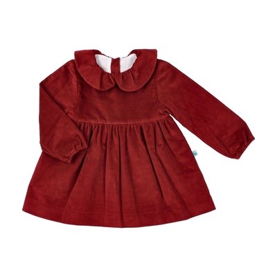 Vista de frente, sobre fundo branco, de vestido bordeaux com gola tulipa. A manga esquerda do vestido está dobrada sobre o corpo. À volta do vestido há texto com destaques informativos: gola em bombazine, tecido em bombazine, forro interior, elástico nos punhos.