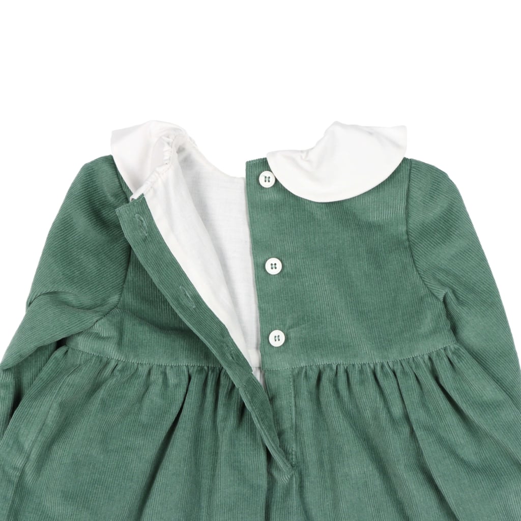 Abertura das costas de um vestido para bebé feito de manga comprida feito em bombazine verde. Vê-se os botões de madrepérola e o forro interior branco.